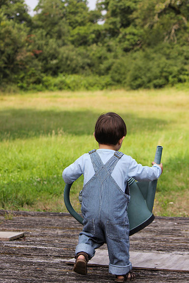 A Little Boy Holding a Large Watering Can