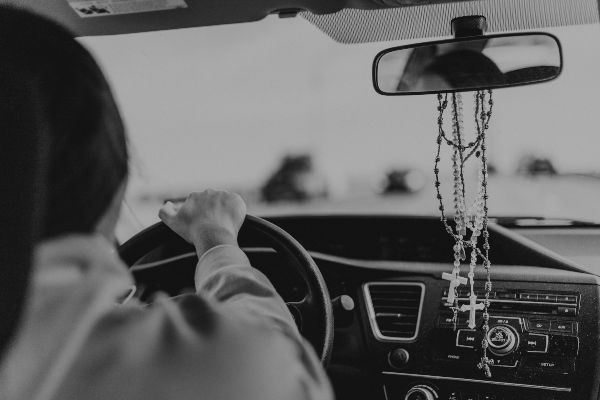 A Girl Driving with Rosaries on her Rearview Mirror