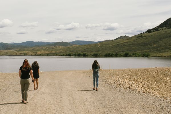 3 Female Students Walking on a Dirt Dorad by a Lake